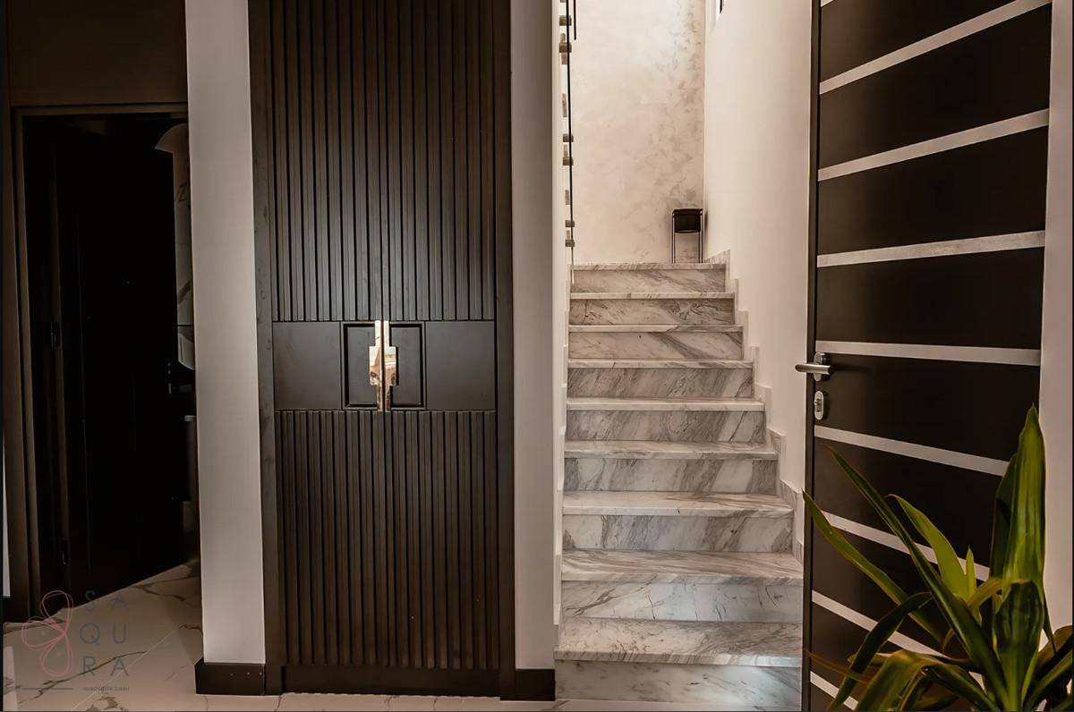 Eleganter Eingangsbereich mit Marmortreppe und modernen Türen, die zu den oberen Etagen führen.
