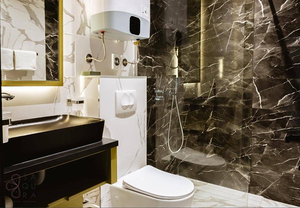 Elegantes Badezimmer mit dunklen Marmorfliesen, moderner Dusche und wandhängendem WC.