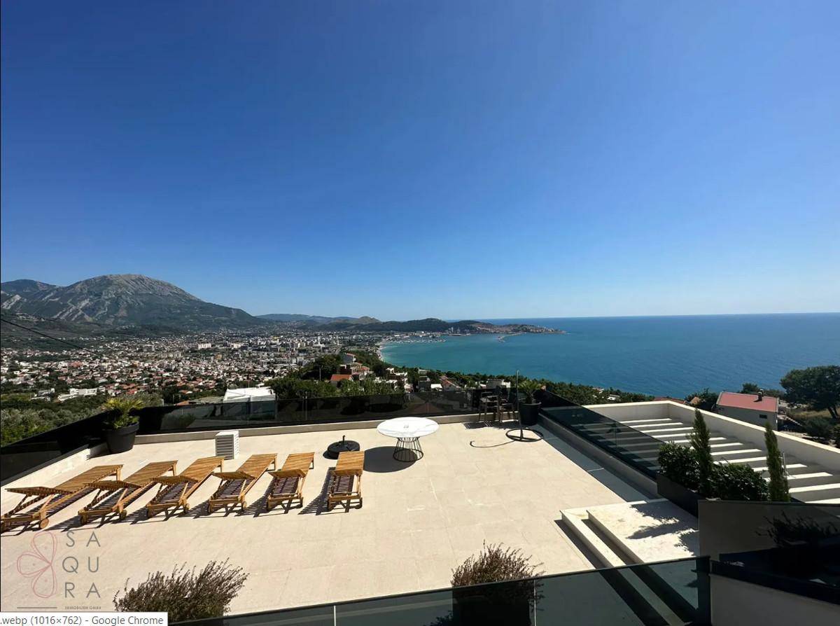Große Dachterrasse mit Sonnenliegen und einem atemberaubenden Panoramablick auf Meer und Berge.
