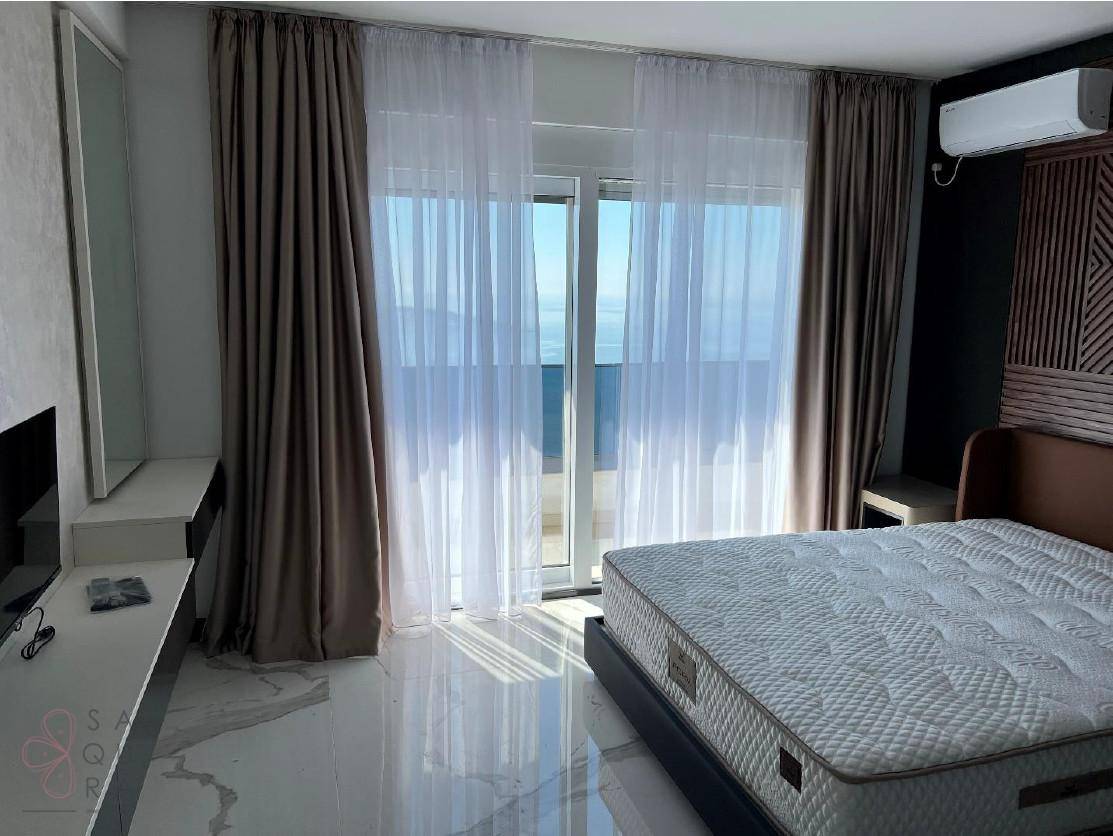 Helles Schlafzimmer mit Meerblick, großem Bett, Schminktisch und direktem Zugang zum Balkon.
