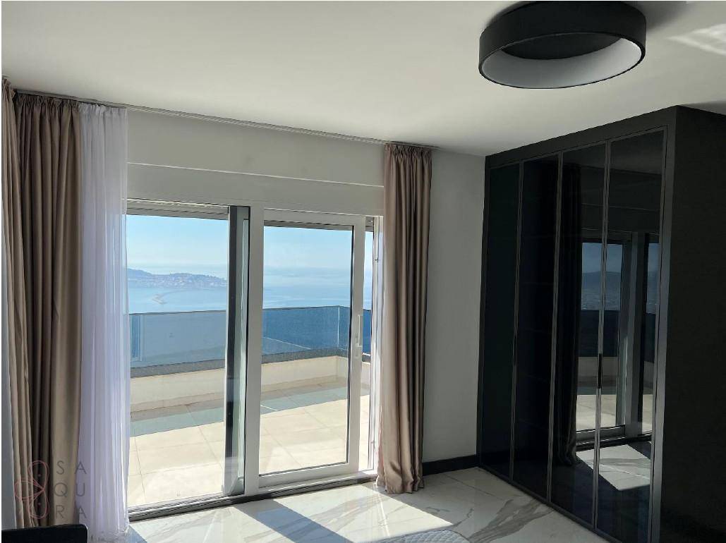 Schlafzimmer mit weitem Meerblick durch große Schiebetüren und einem eleganten Einbauschrank.