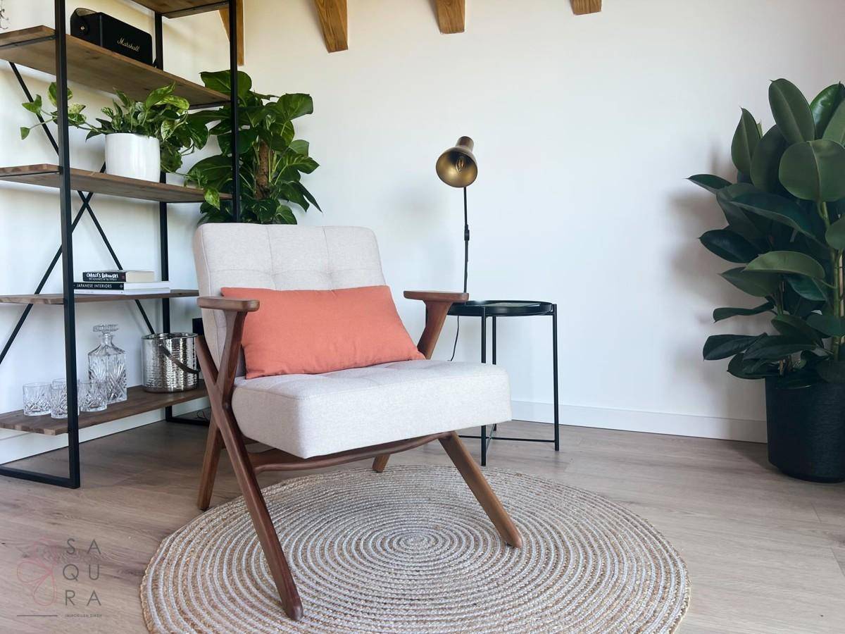 Gemütliche Leseecke mit modernem Sessel, Pflanzen und einem Bücherregal.