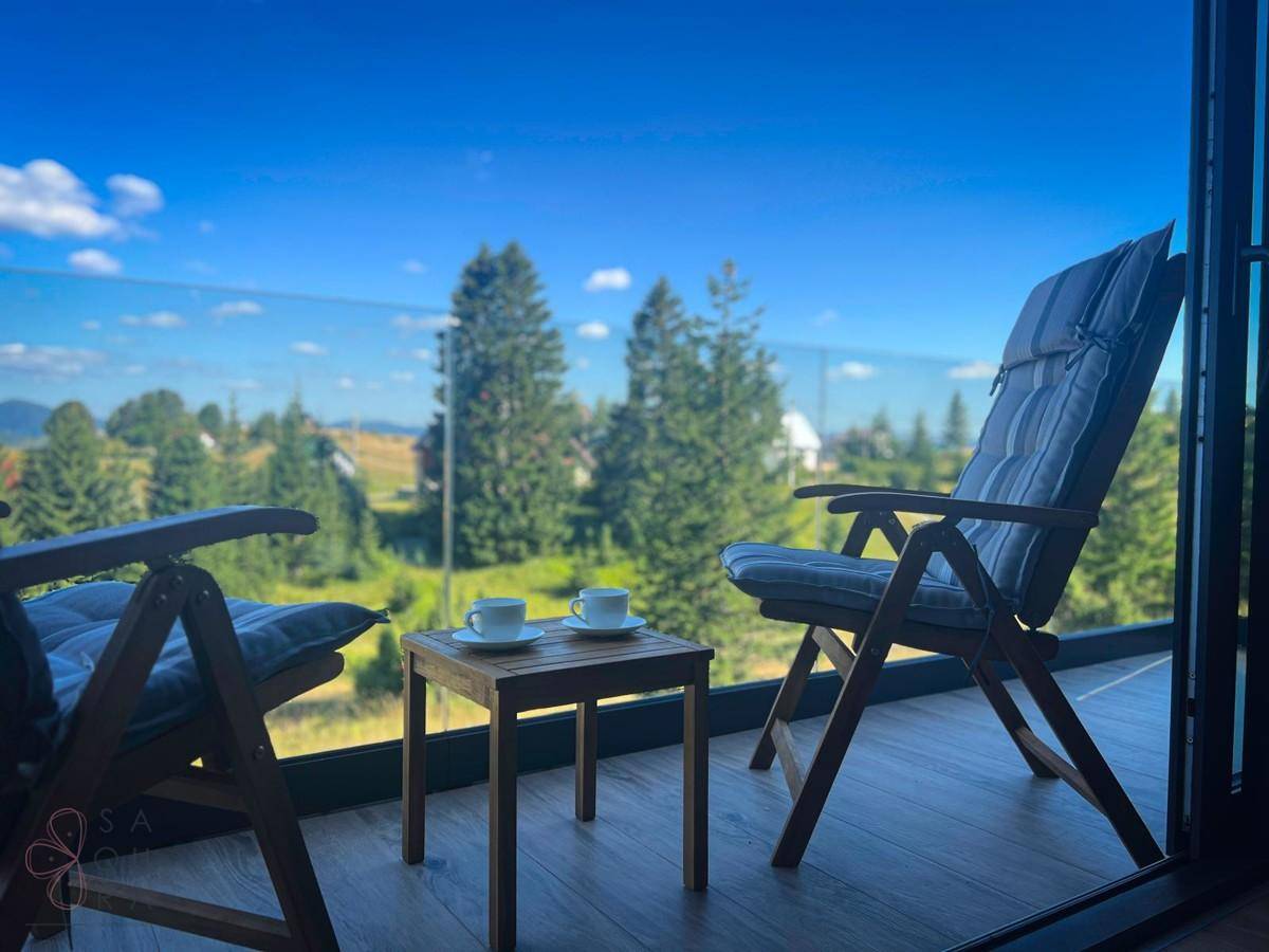 Gemütlicher Balkon mit Sitzgelegenheiten und weitem Blick über die grüne Landschaft.