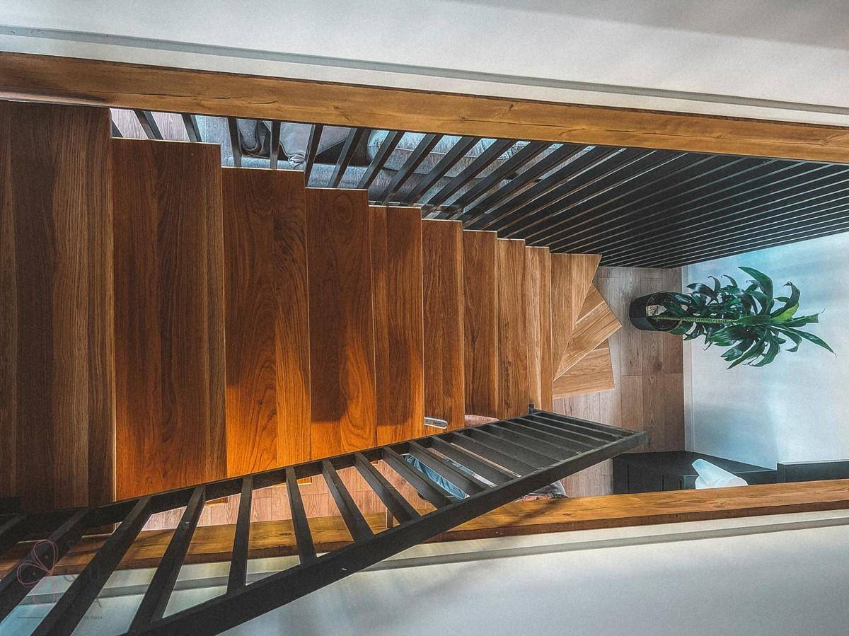 Elegante Holztreppe mit schwarzem Geländer, die die verschiedenen Ebenen des Hauses verbindet.