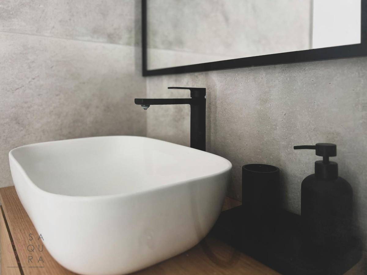 Moderner Waschtisch mit Aufsatzwaschbecken und schwarzem Wasserhahn in einem Badezimmer.