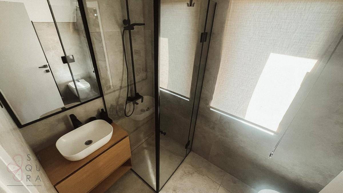 Modernes Badezimmer mit begehbarer Dusche, Aufsatzwaschbecken und grauen Fliesen.