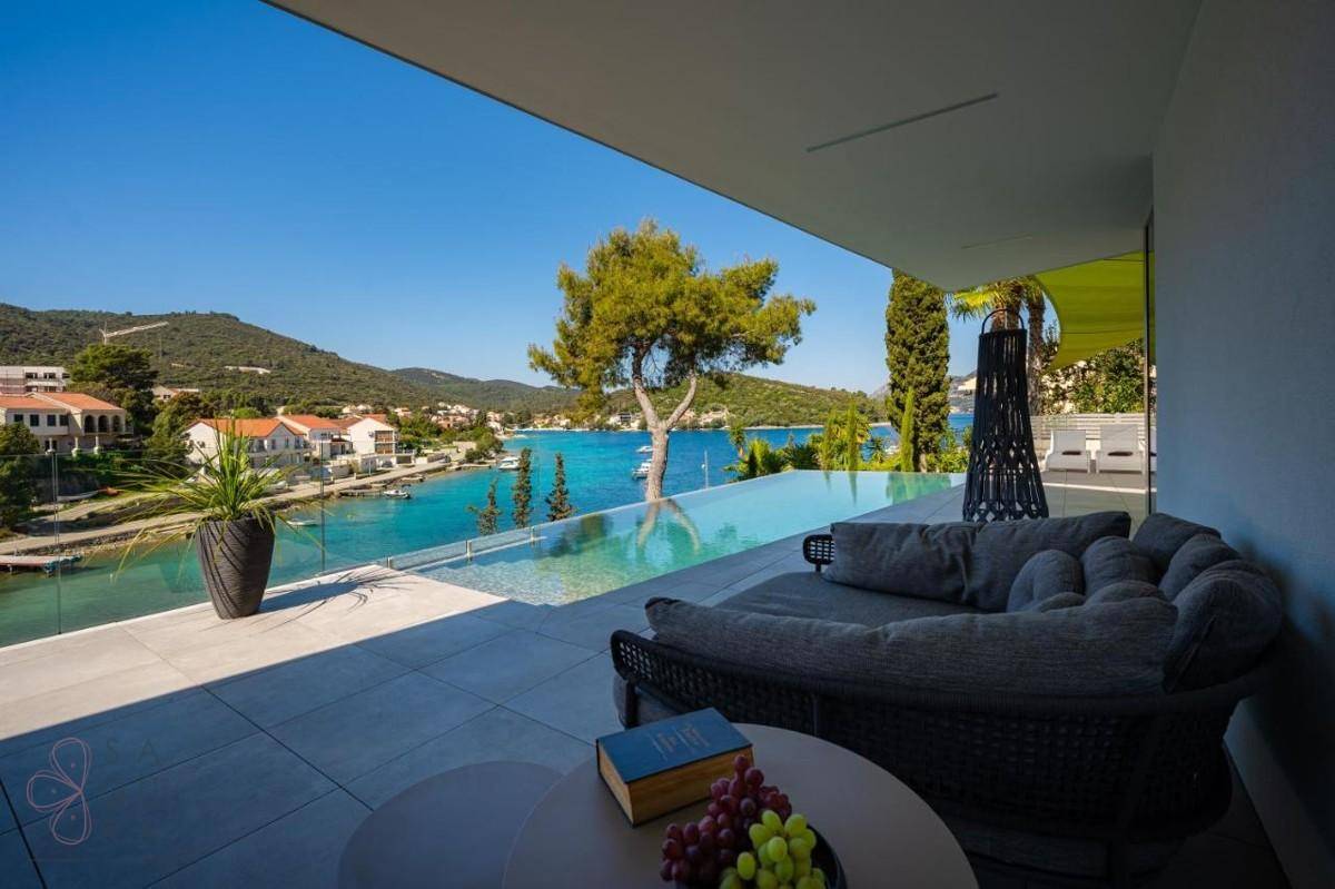 Luxuriöse Terrasse mit Infinity-Pool, bequemen Lounge-Möbeln und atemberaubendem Meerblick auf die Bucht.