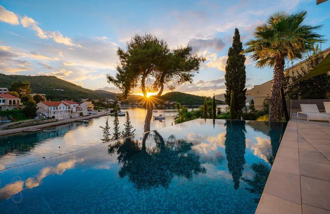 Atemberaubender Sonnenuntergang über dem Infinity-Pool mit Blick auf die Küstenlandschaft.