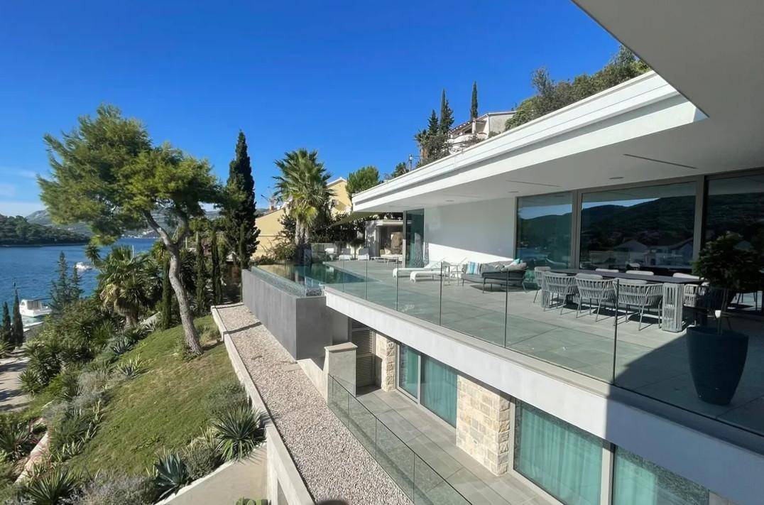 Mehrere Terrassen der Villa mit Außenmöbeln und Panoramablick auf das glitzernde Meer.