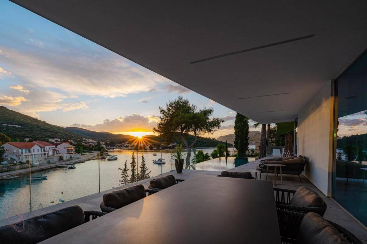 Spektakuläre Terrasse mit Esstisch und Panoramablick auf das Meer bei Sonnenuntergang.