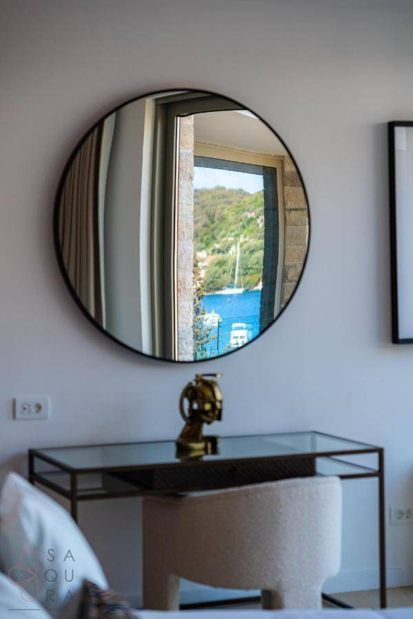 Runder Spiegel über einem Schminktisch im Schlafzimmer, der den Meerblick reflektiert.