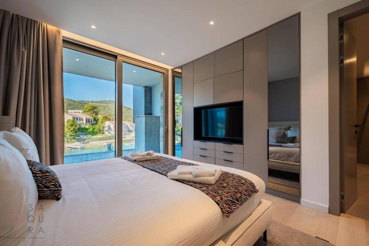Schlafzimmer mit großem Bett, Einbauschränken und raumhohen Fenstern mit Meerblick.