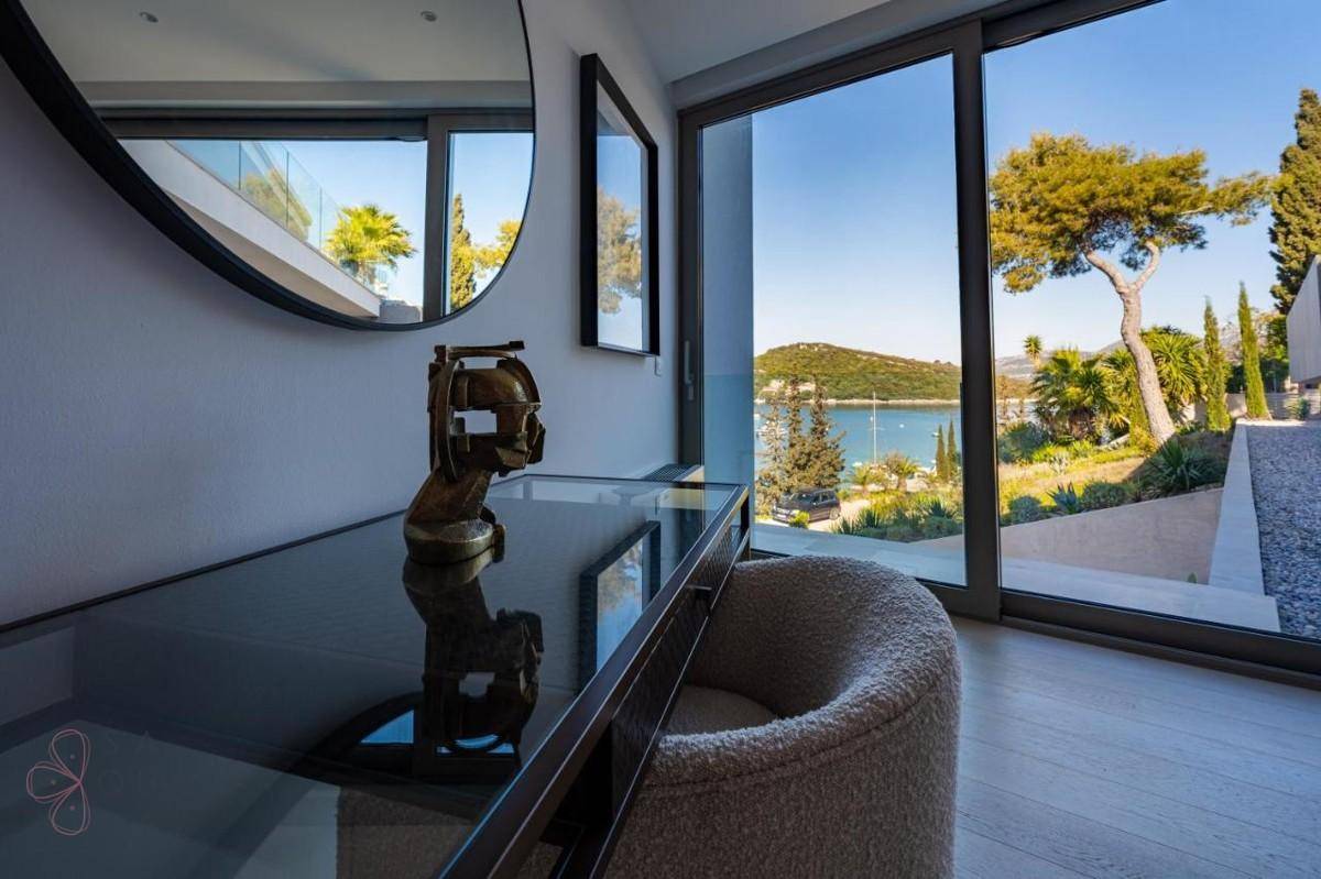 Heller Arbeitsbereich mit Meerblick durch große Glasschiebetüren und moderner Einrichtung.