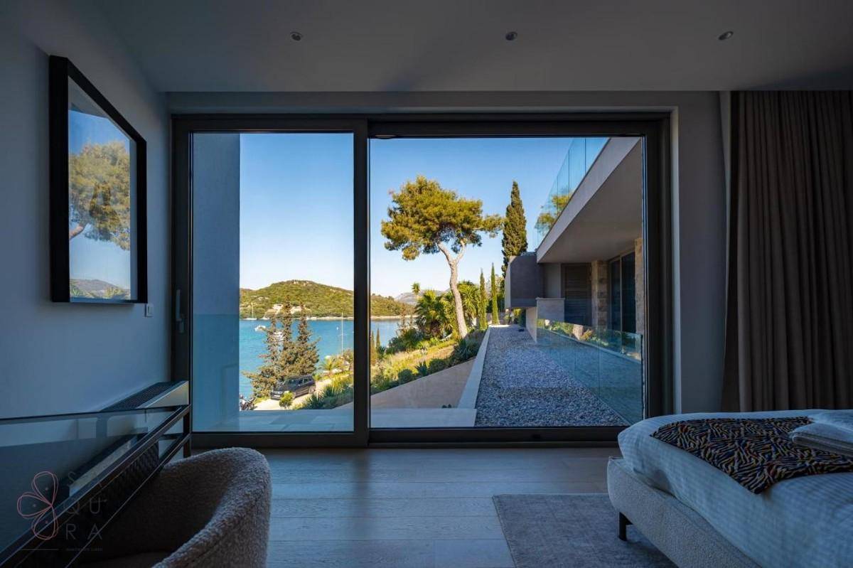 Schlafzimmer mit atemberaubendem Meerblick durch große Glasschiebetüren und hellem Interieur.