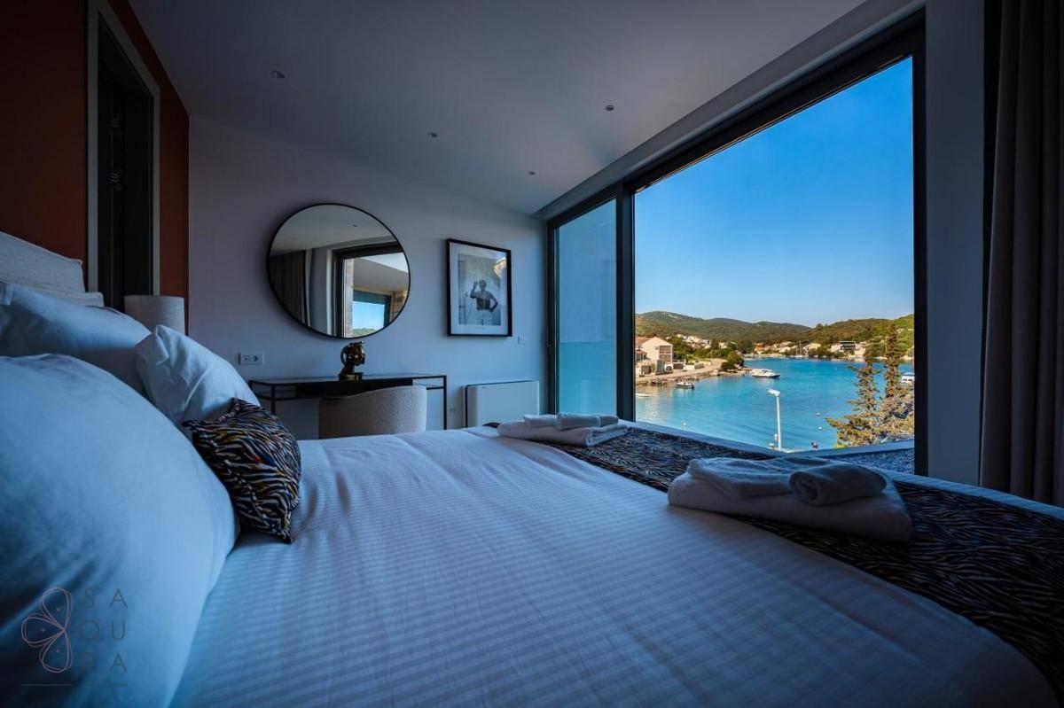 Komfortables Schlafzimmer mit großem Bett, rundem Spiegel und raumhohen Fenstern mit Meerblick.