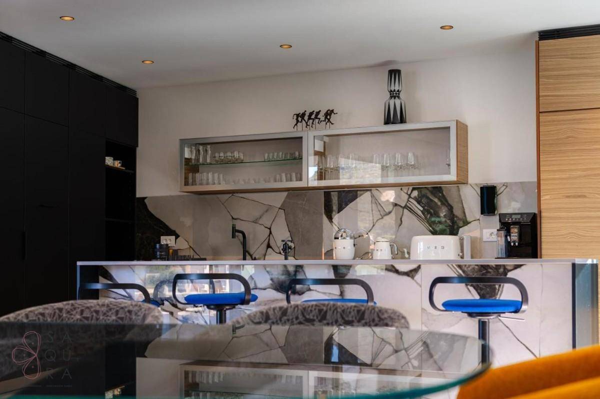 Moderne Küche mit Frühstücksbar, blauen Hockern und auffälliger Rückwandgestaltung.