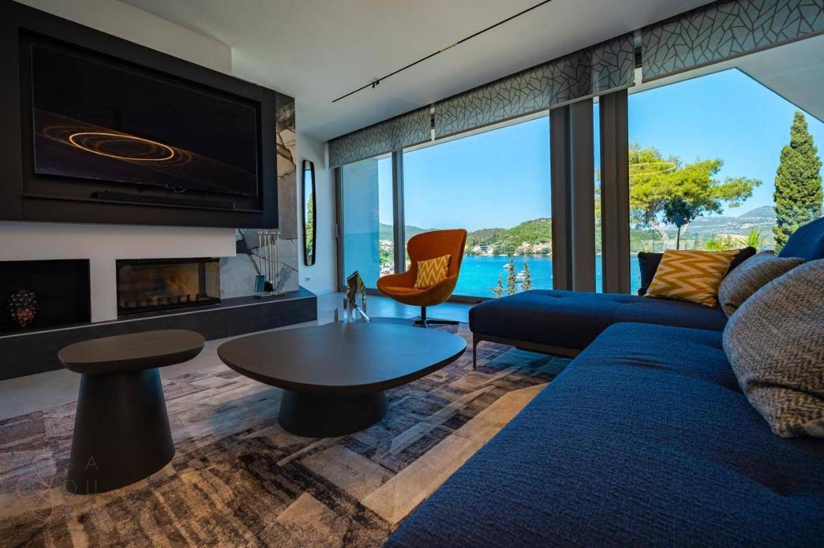 Elegantes Wohnzimmer mit blauem Sofa, Kamin und Panoramafenstern mit weitem Meerblick.