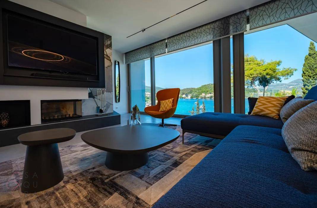 Stilvolles Wohnzimmer mit großem Sofa, Kamin und Panoramafenstern mit weitem Meerblick.