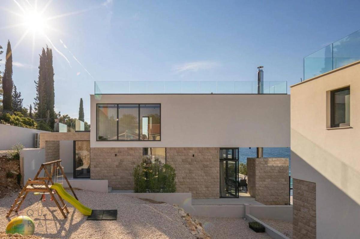 Moderne Villa mit Steinfassade, großen Fenstern und einem Spielplatz im Außenbereich.