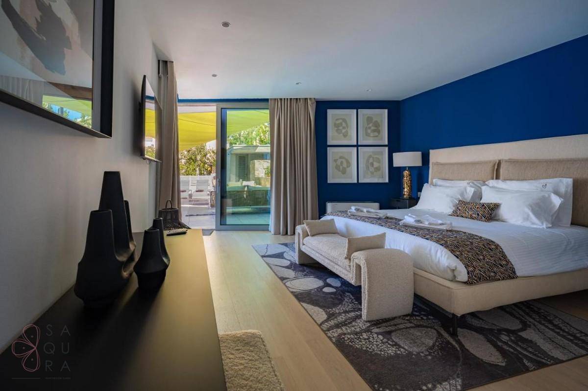 Stilvolles Schlafzimmer mit blauer Wand, Zugang zur Terrasse und moderner Einrichtung.