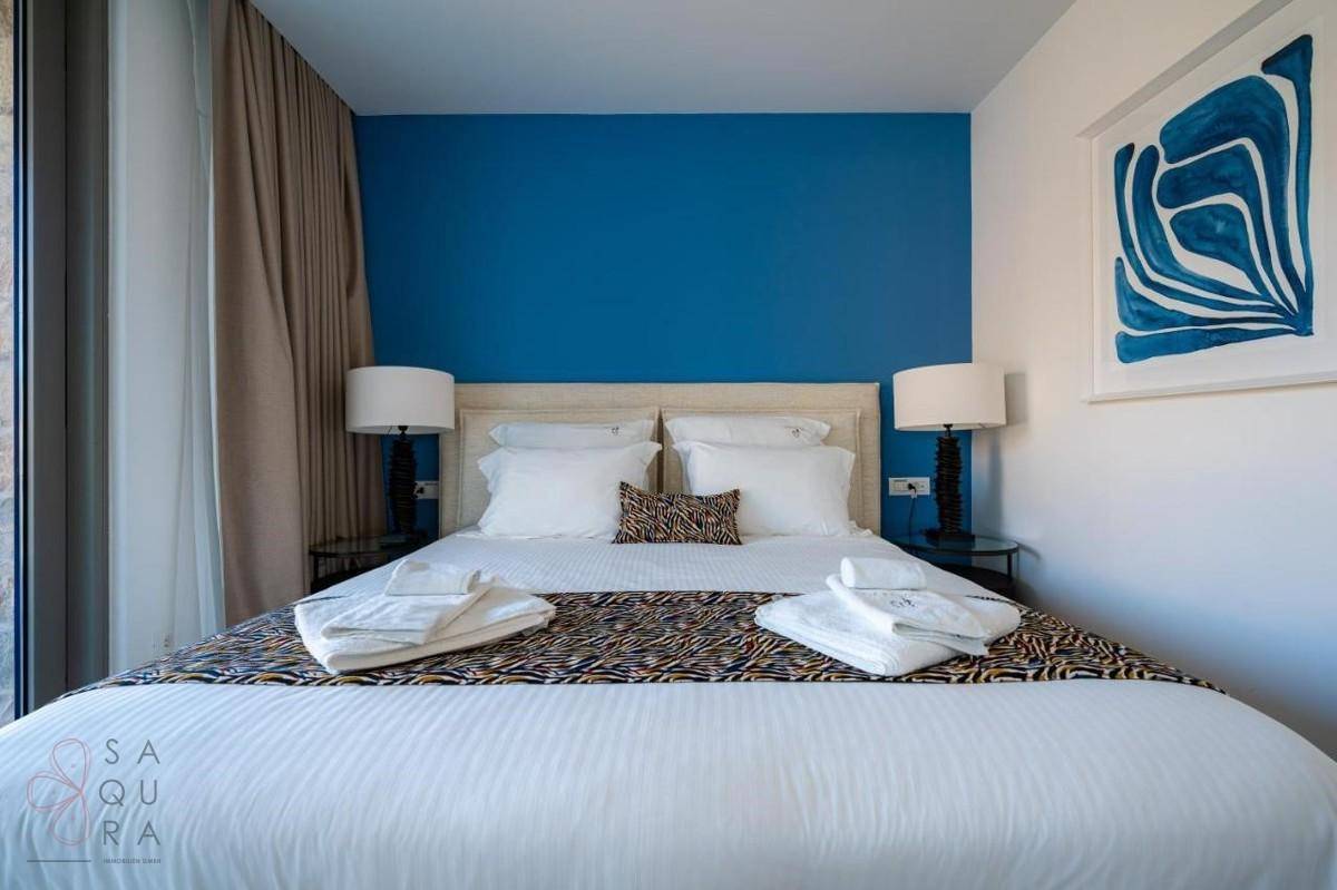 Komfortables Schlafzimmer mit blauer Akzentwand, großem Bett und moderner Kunst an der Wand.