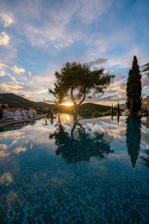 Atemberaubender Infinity-Pool bei Sonnenuntergang mit Spiegelung des Himmels und der Bäume.
