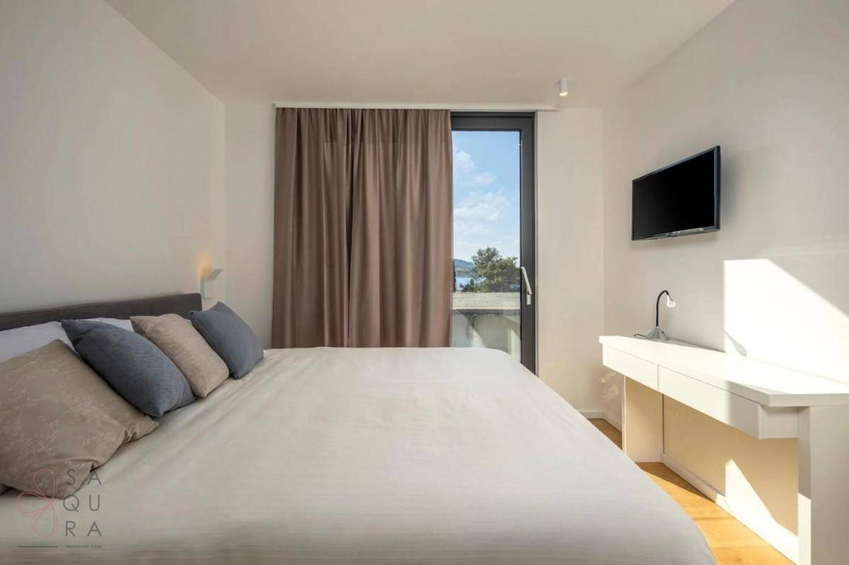 Helles Schlafzimmer mit Doppelbett, Schreibtisch und Zugang zu einem Balkon mit Meerblick.