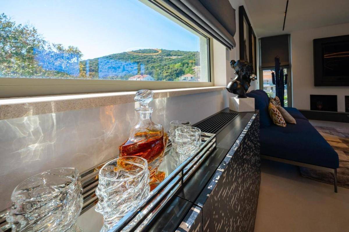 Elegantes Sideboard mit Getränken und einem Fenster mit weitem Blick auf die grüne Hügellandschaft.