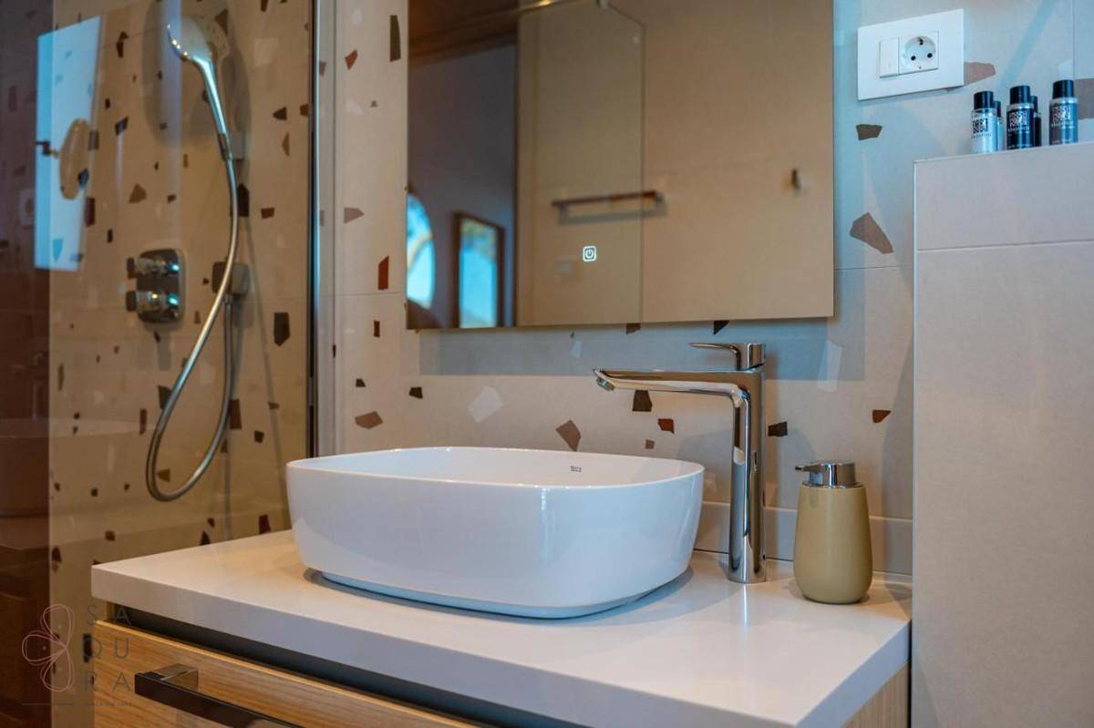 Modernes Badezimmer mit Aufsatzwaschbecken, Spiegelschrank und begehbarer Dusche.