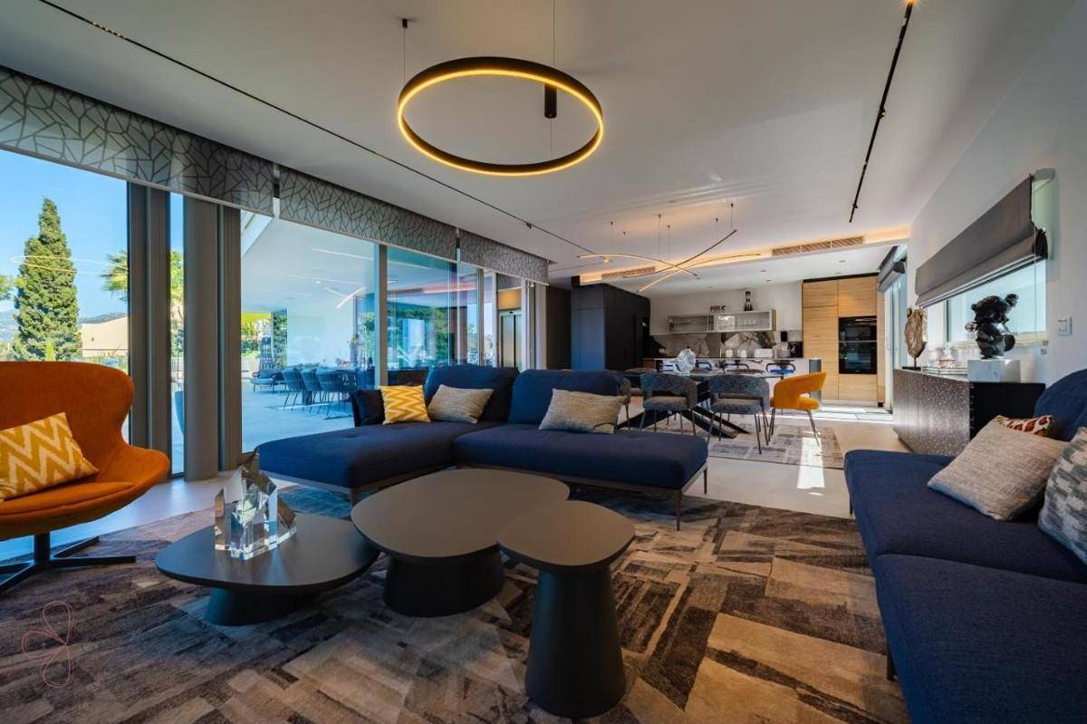 Geräumiger offener Wohnbereich mit blauen Sofas, modernen Leuchten und Blick auf die Küche.