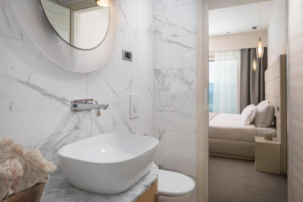Modernes Badezimmer mit Marmorfliesen, stilvollem Waschbecken und Blick in das angrenzende Schlafzimmer.