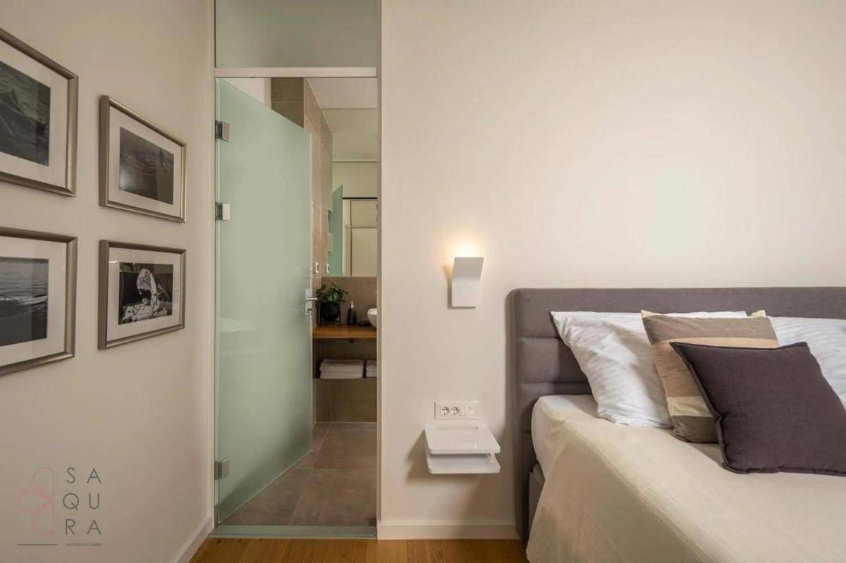Gemütliches Schlafzimmer mit Doppelbett und angrenzendem Badezimmer, getrennt durch eine Glastür.