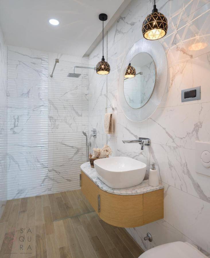Elegantes Badezimmer mit Marmorfliesen, schwebendem Waschtisch, Aufsatzwaschbecken und begehbarer Dusche.