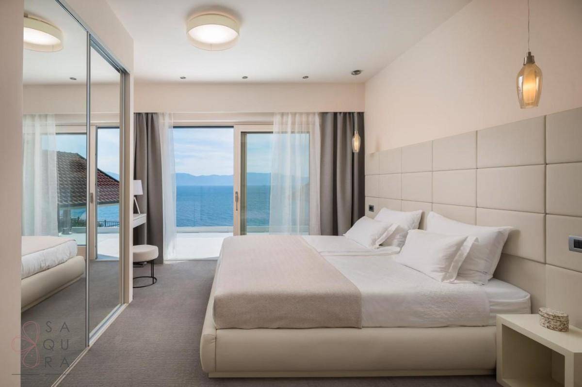 Geräumiges Schlafzimmer mit großem Bett, Spiegelschränken und Balkonzugang mit herrlichem Meerblick.