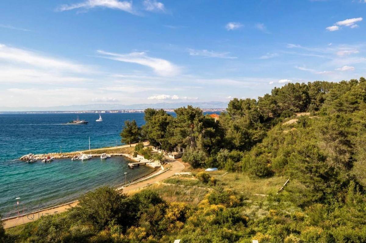 Panoramablick auf die Küste mit üppiger Vegetation, blauem Meer und kleinen Booten.