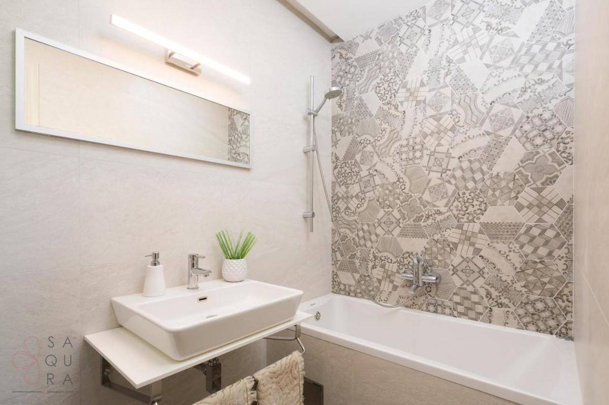 Modernes Badezimmer mit Badewanne, Duschfunktion und dekorativen Fliesen an der Wand.