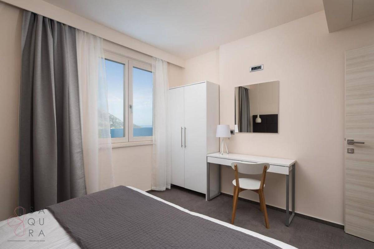 Helles Schlafzimmer mit Meerblick, weißem Kleiderschrank und modernem Schreibtisch.