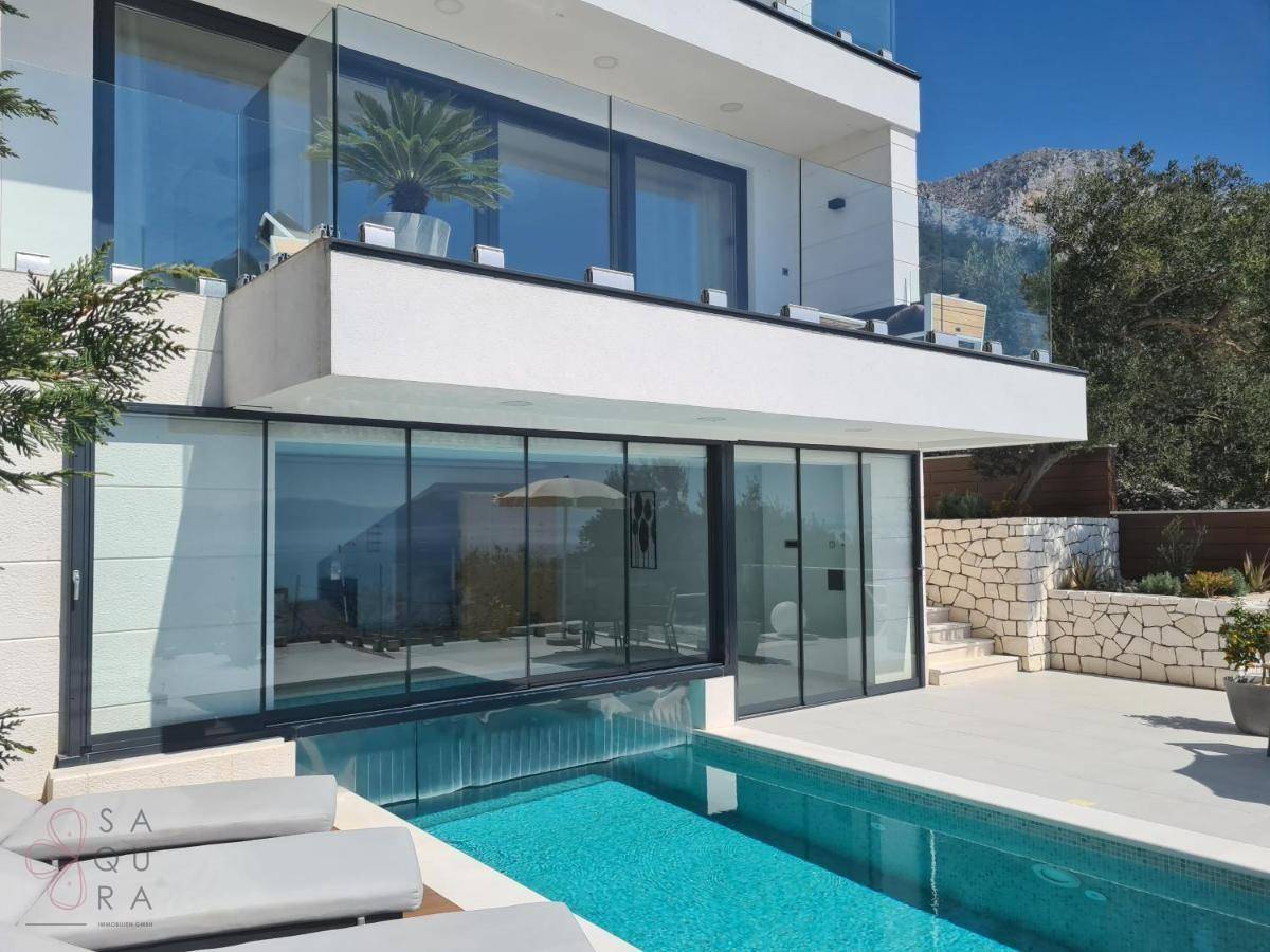 Moderne Villa mit großzügiger Glasfassade, Pool und Meerblick in sonniger Lage.