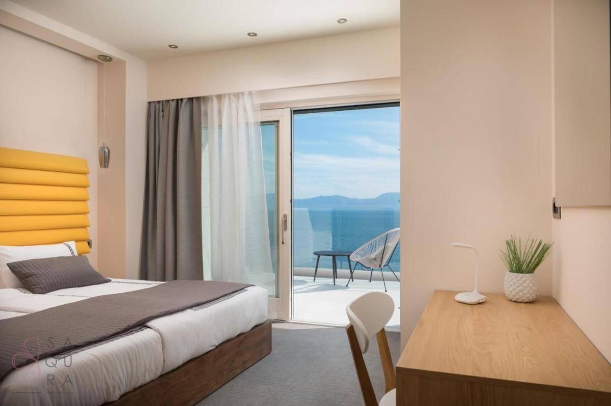 Gemütliches Schlafzimmer mit gelbem Kopfteil, Meerblick und Zugang zu einem Balkon.