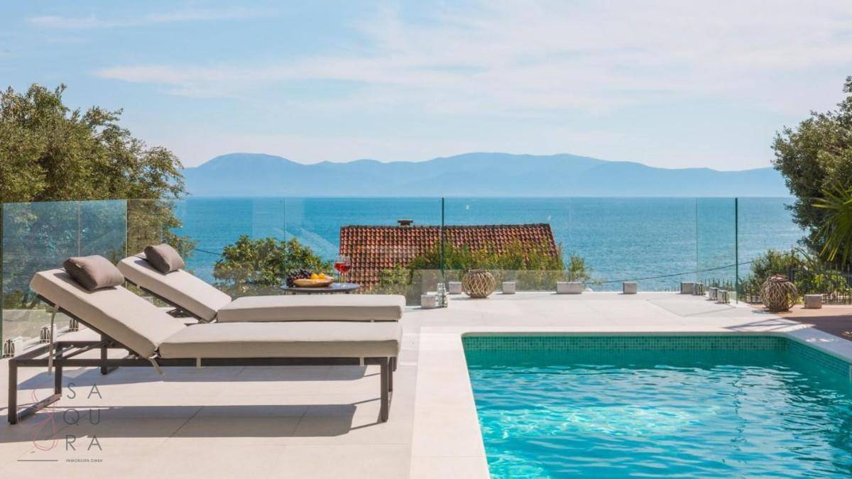 Geräumiger Poolbereich mit Sonnenliegen und einem atemberaubenden Panoramablick auf das Meer und die Küste.