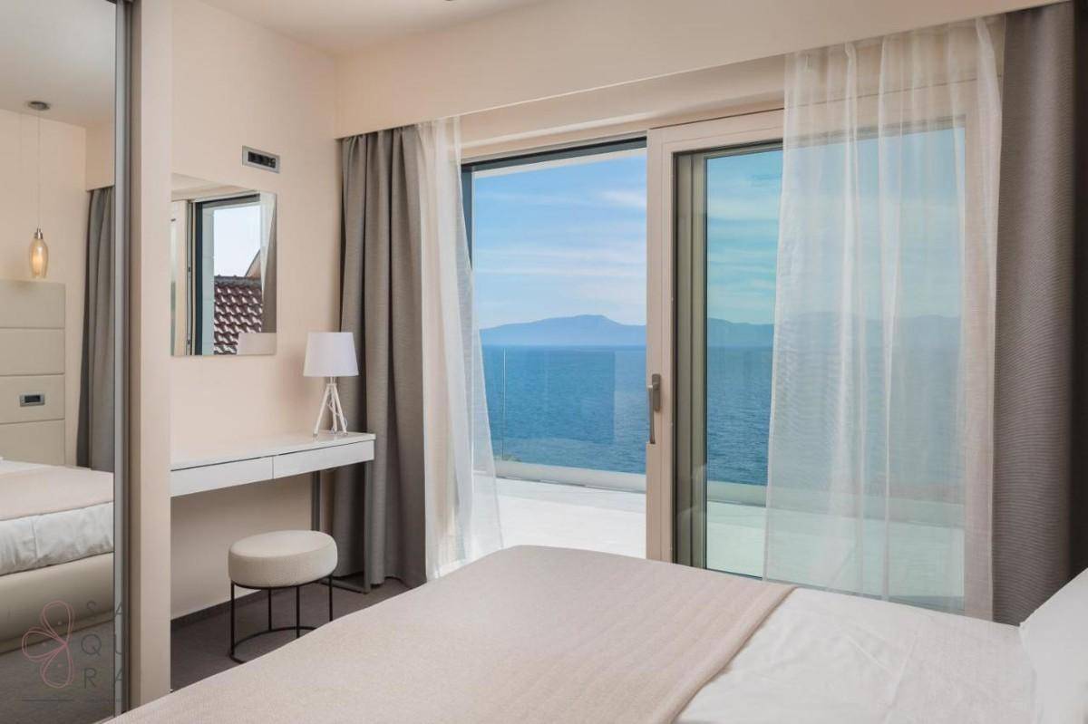 Helles Schlafzimmer mit Meerblick, großem Fenster und modernem Schminktisch.