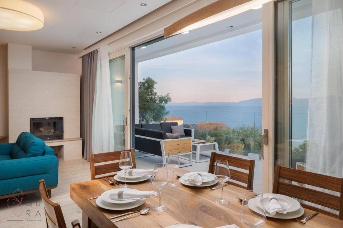 Eleganter Essbereich mit Holztisch, Meerblick und Zugang zur Außenterrasse.
