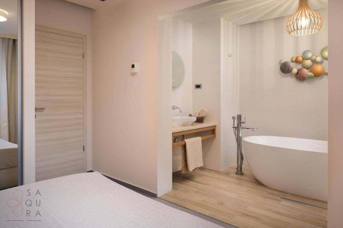 Elegantes Badezimmer mit freistehender Badewanne und Holzboden, direkt vom Schlafzimmer zugänglich.