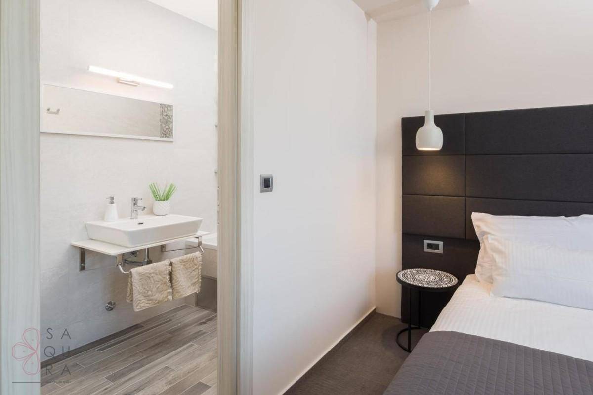 Helles Badezimmer mit modernem Waschbecken, direkt verbunden mit einem Schlafzimmer.