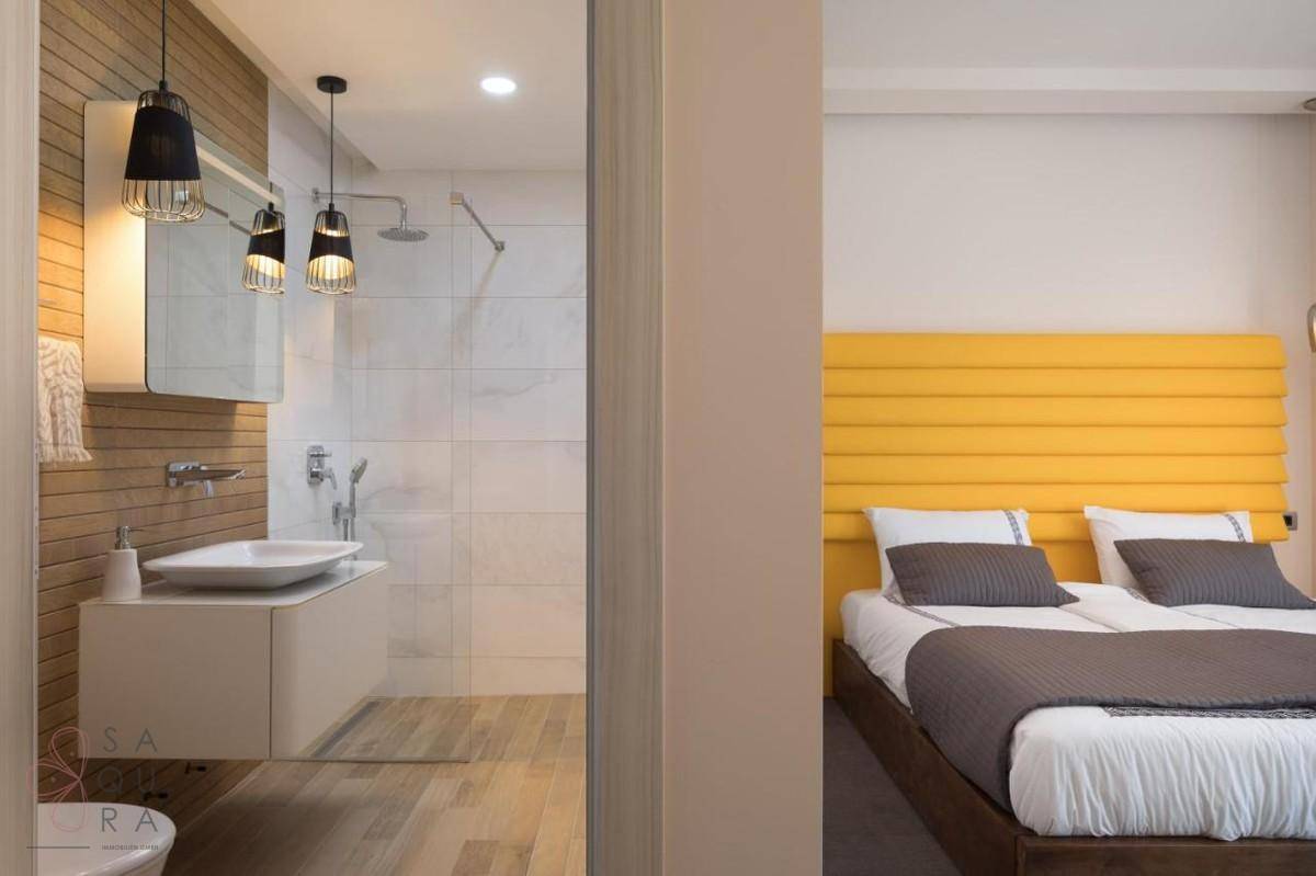 Modernes Badezimmer mit Holzdetails und begehbarer Dusche, direkt neben einem Schlafzimmer.