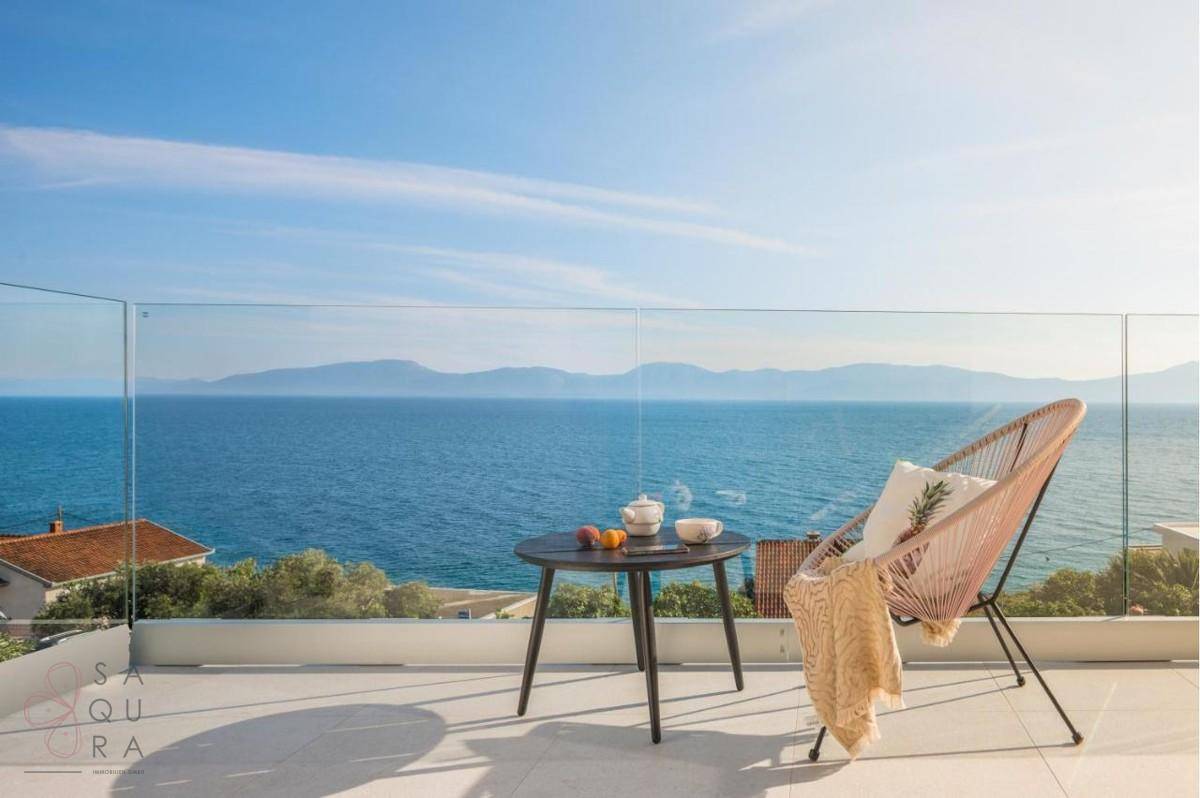 Sonniger Balkon mit bequemen Sitzgelegenheiten und weitem Blick über das Meer.