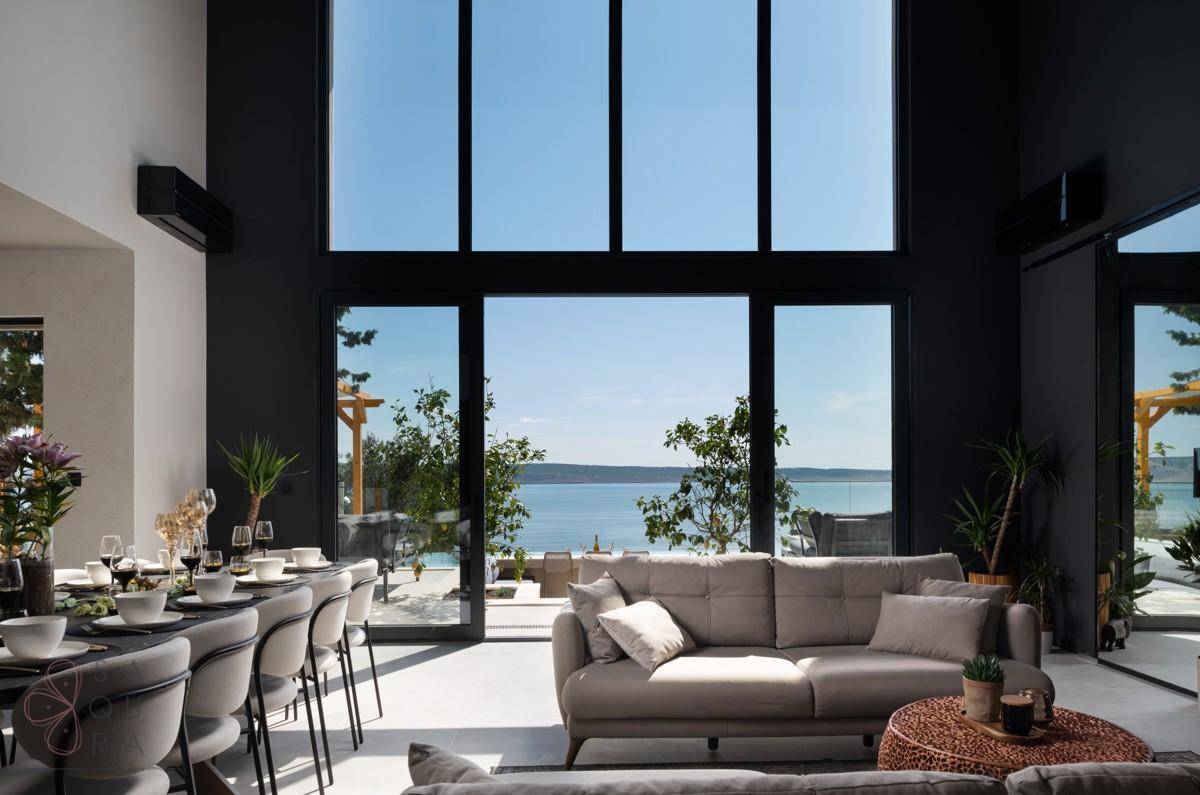 Heller Wohn- und Essbereich mit hohen Decken und Panoramafenstern, die einen weiten Meerblick bieten.