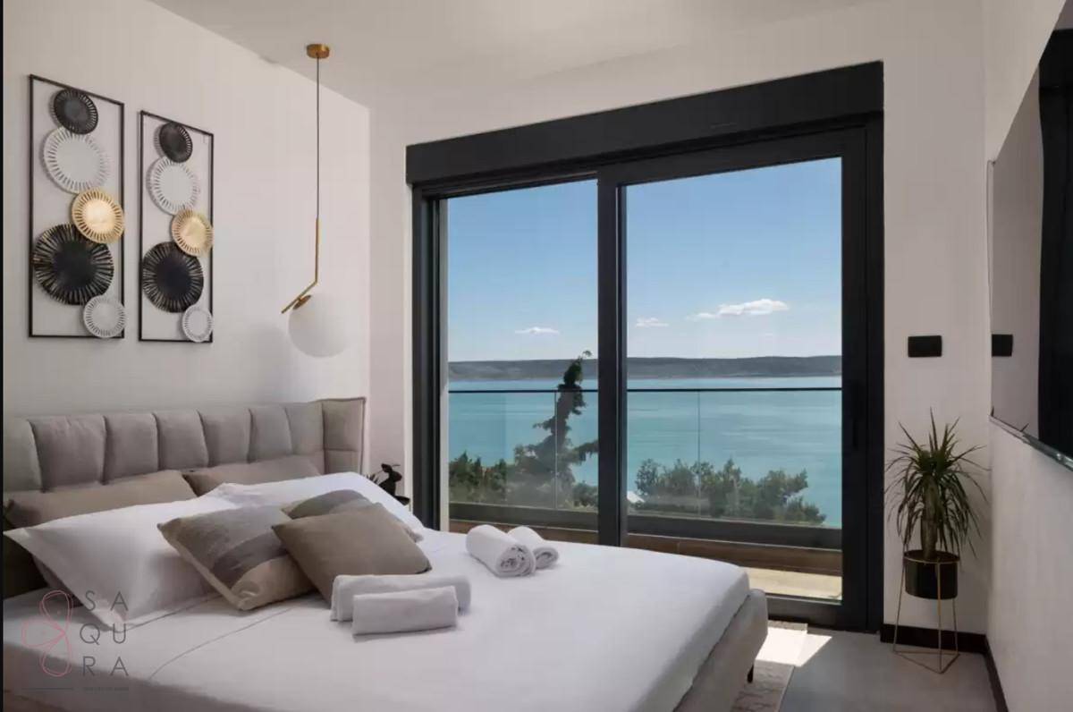 Modernes Schlafzimmer mit großem Bett und Schiebetüren, die einen direkten Meerblick ermöglichen.