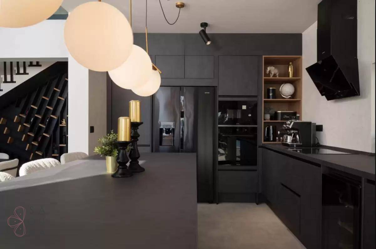 Elegante schwarze Küche mit modernen Geräten, Kochinsel und stilvoller Beleuchtung.