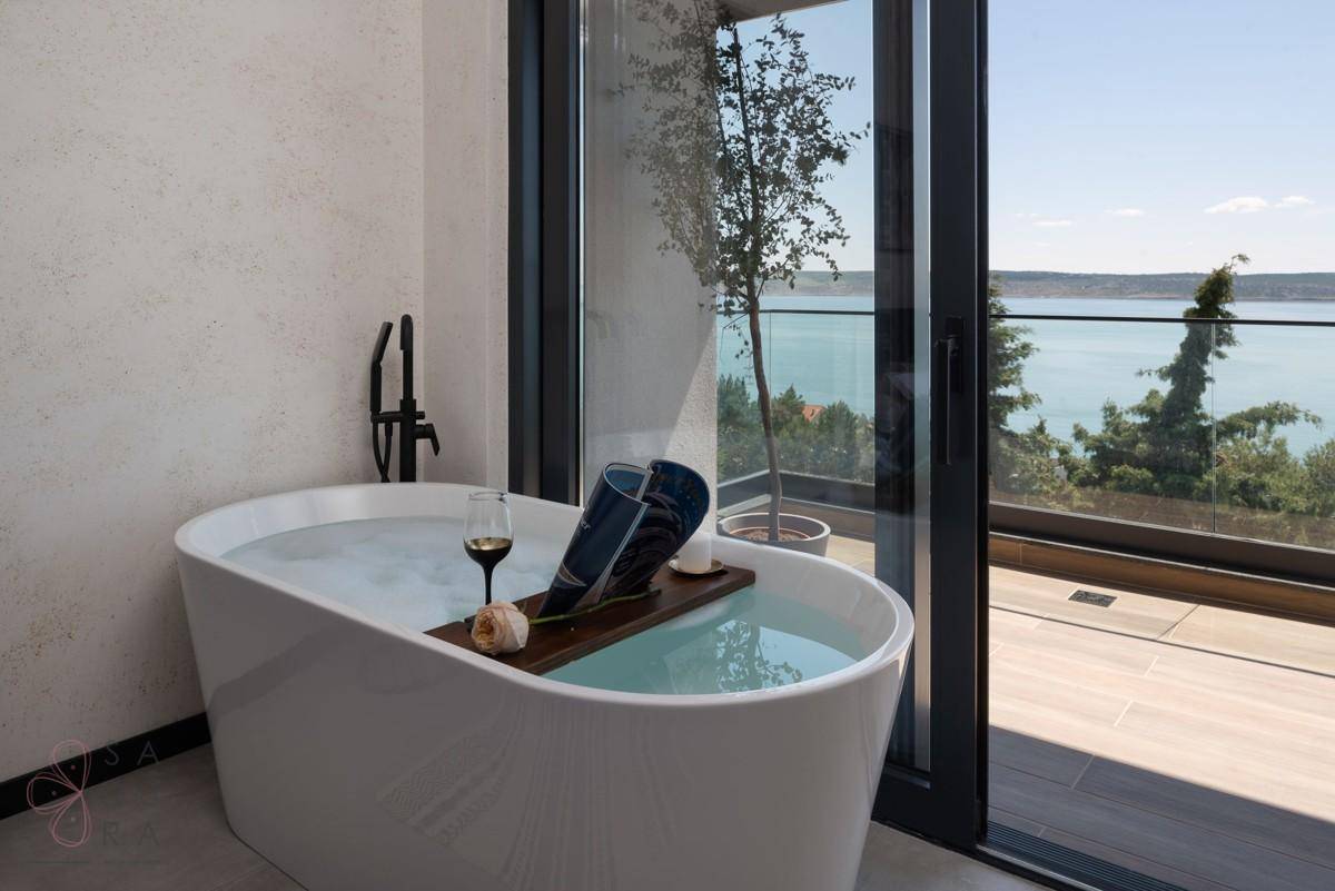 Freistehende Badewanne im Schlafzimmer mit Blick auf das Meer und die umliegende Landschaft.